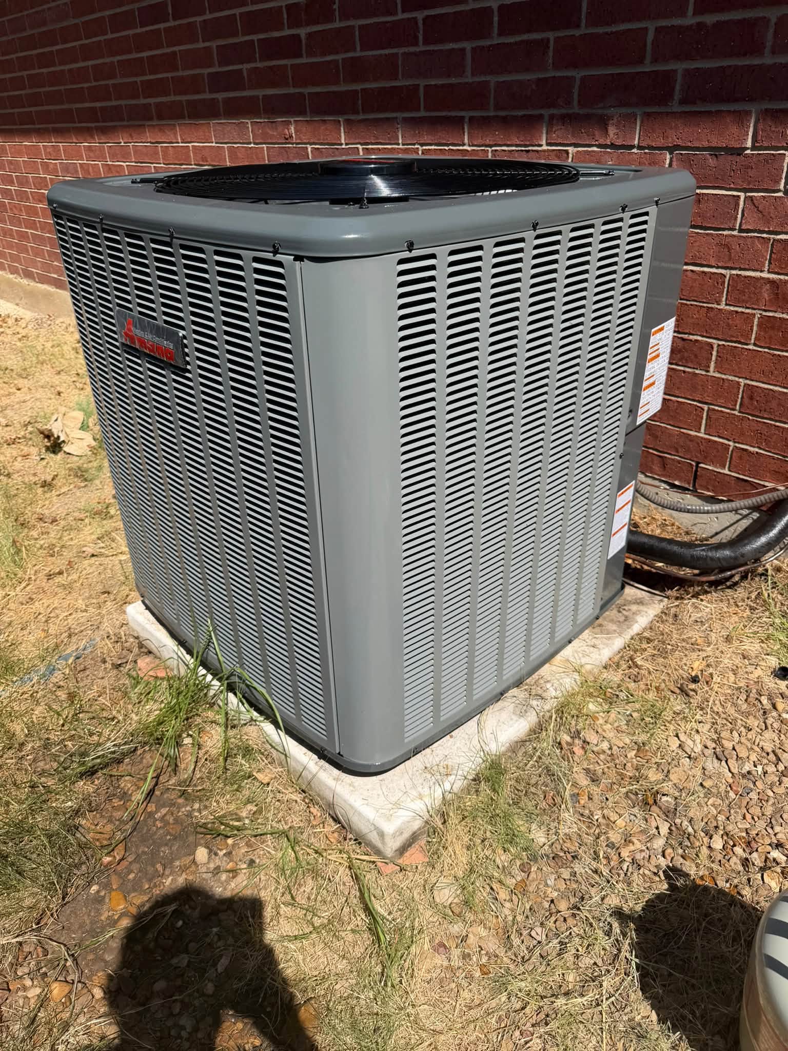 Outdoor condensing unit beside a brick wall
